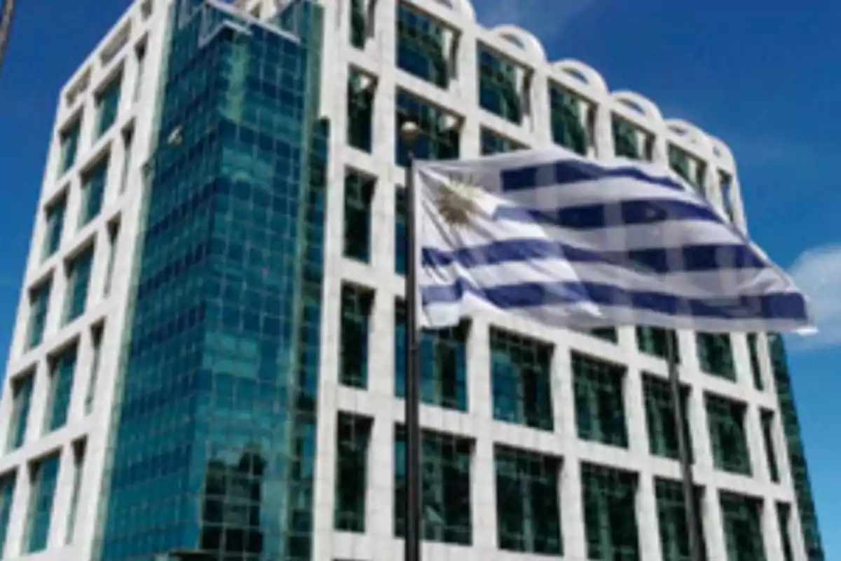 Modern building with a glass facade and the Uruguayan flag waving in the foreground.