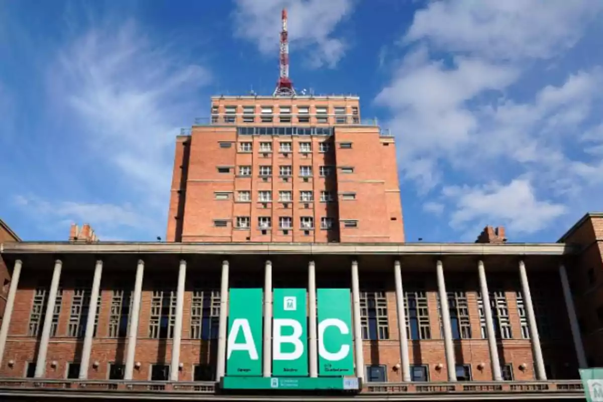 Brick building with columns and an antenna on top under a blue sky.