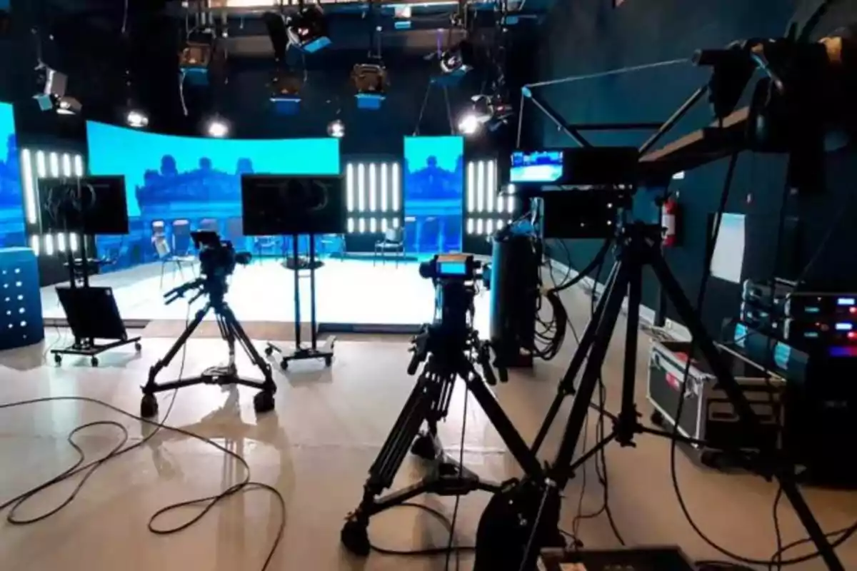 A recording studio with multiple cameras and screens, studio lights, and technical equipment.