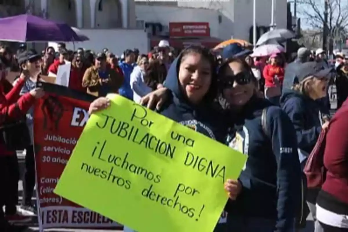 Personas en una manifestación sostienen un cartel que dice 