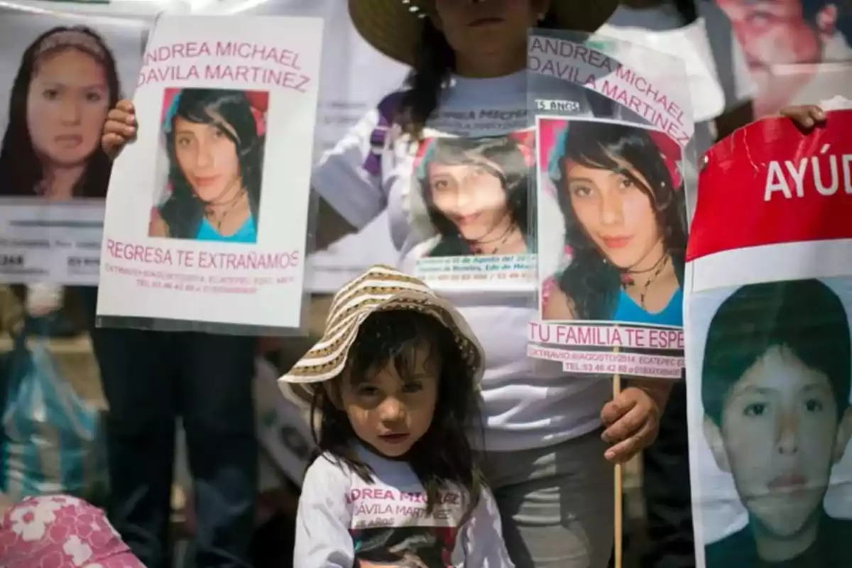 Un grupo de personas sostiene carteles de búsqueda de personas desaparecidas, incluyendo una niña pequeña con un sombrero.