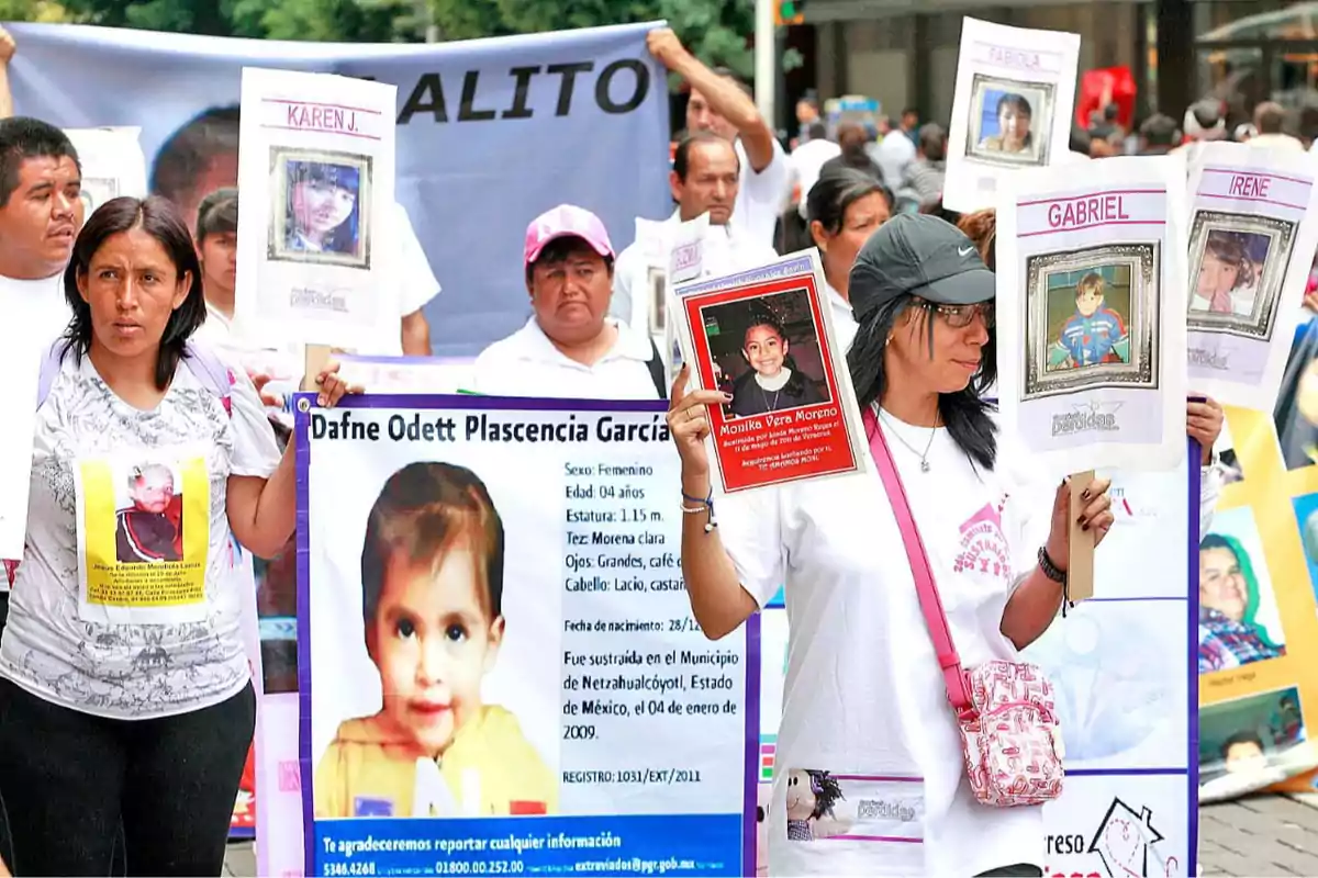 Personas participando en una marcha sosteniendo carteles con fotos de niños desaparecidos.