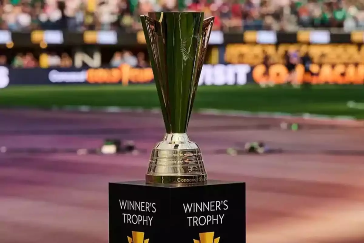 Trofeo de campeón en un estadio con fondo desenfocado.