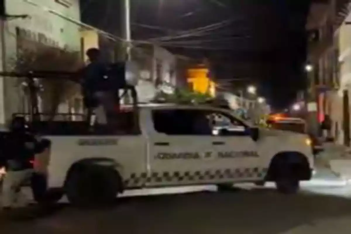 Una camioneta de la Guardia Nacional circula por una calle iluminada durante la noche.