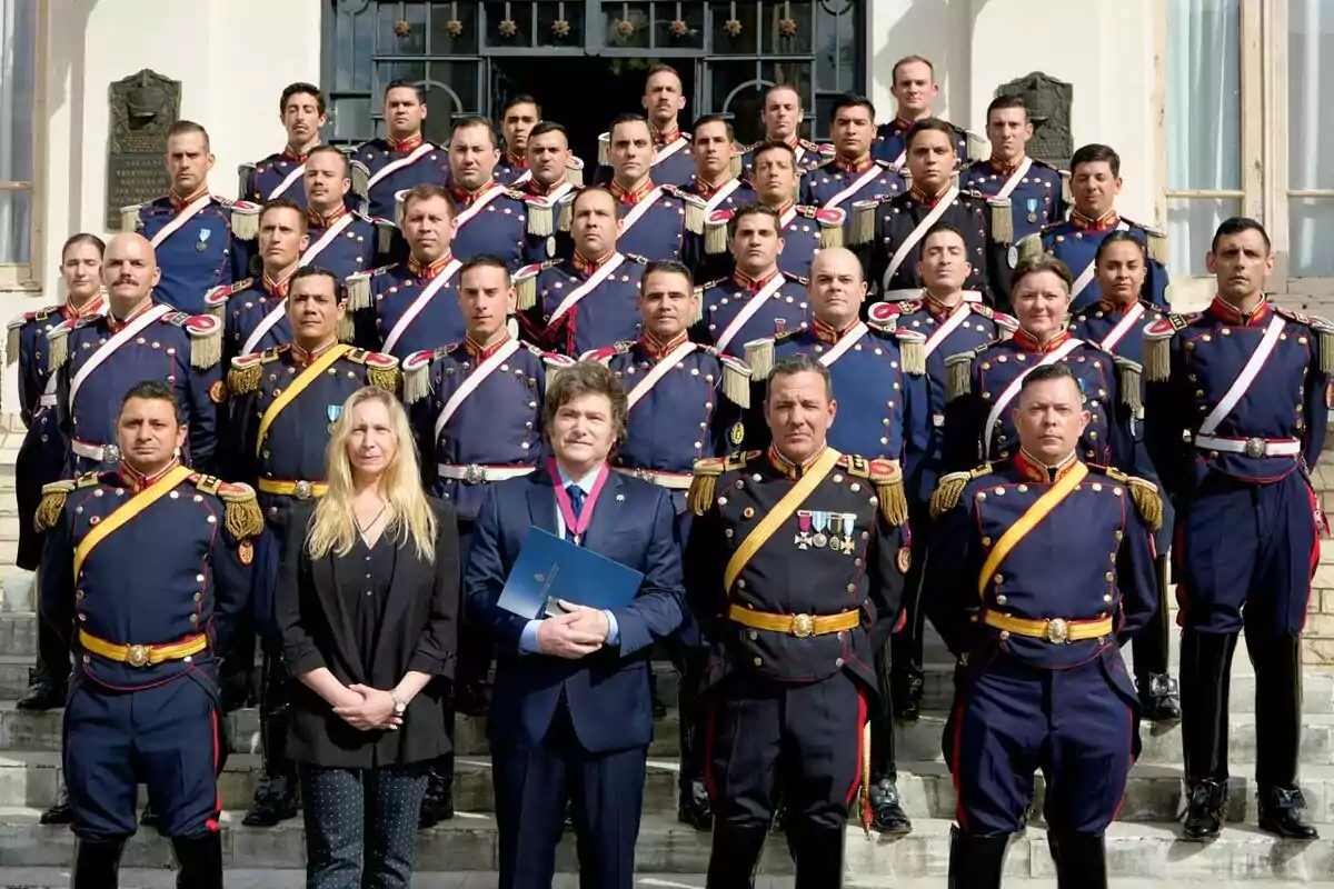 Un grupo de personas posando en una escalera, la mayoría con uniformes militares formales y dos personas en el centro con ropa de civil. Un grupo de personas posando en una escalera, la mayoría con uniformes militares formales y dos personas en el centro con ropa de civil.