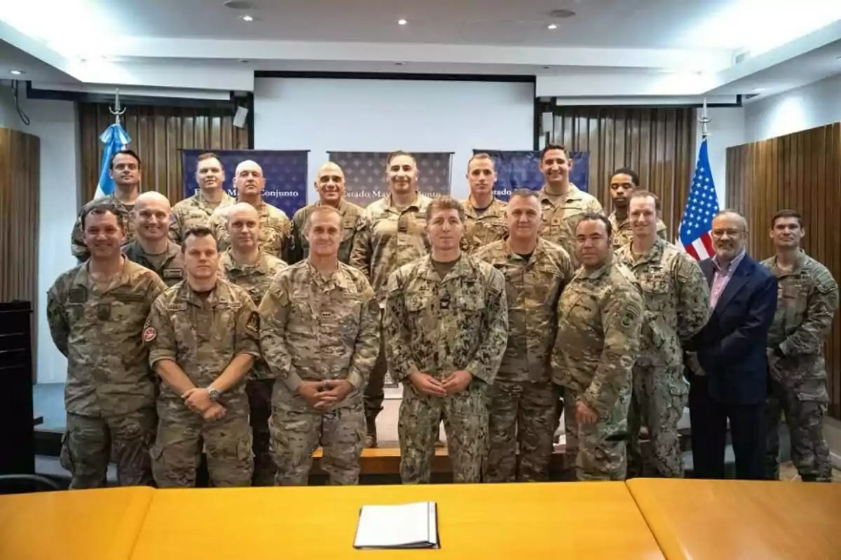 A group of people in military uniform posing for a photo in a room with Argentine and United States flags in the background. A group of people in military uniform posing for a photo in a room with Argentine and United States flags in the background.