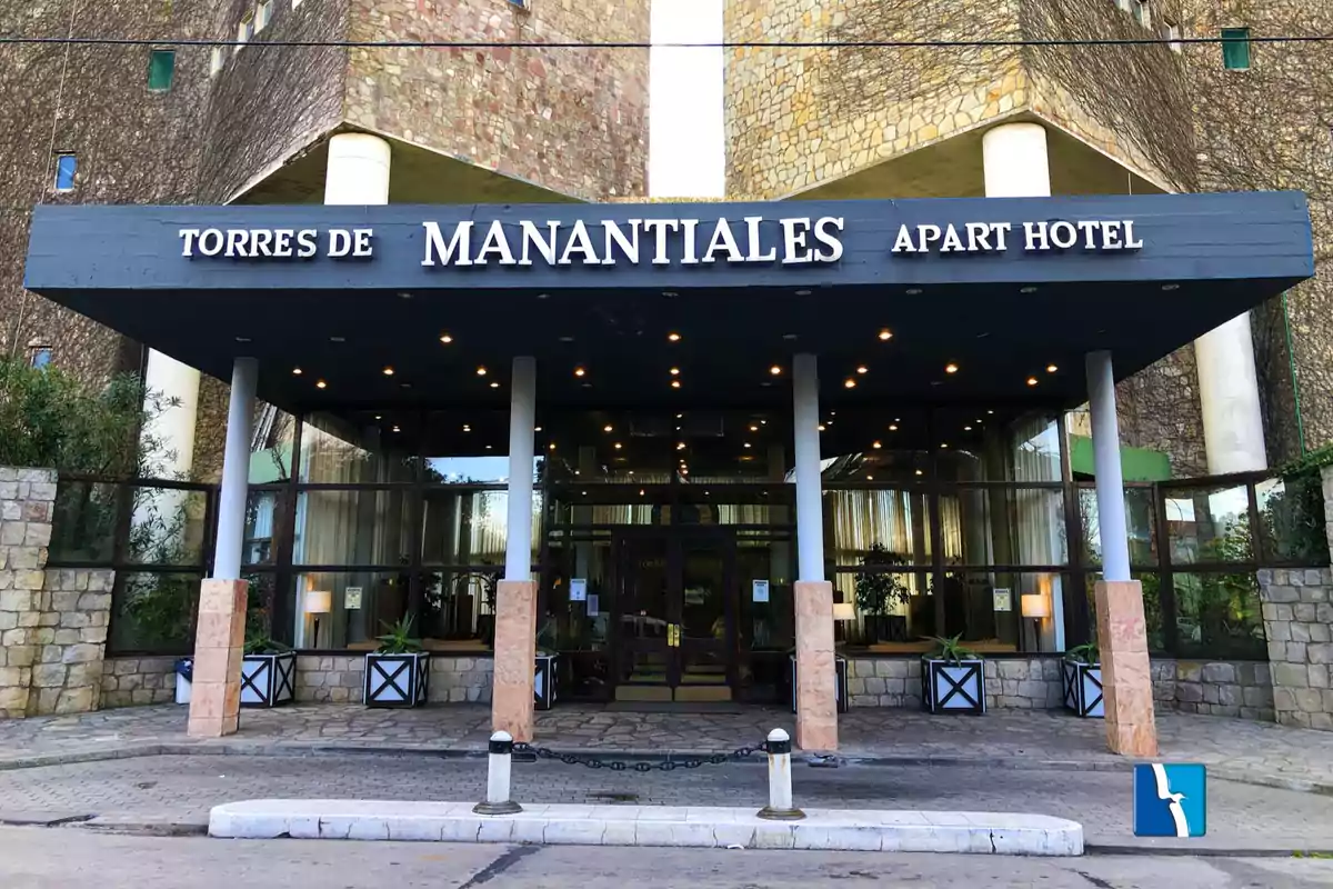 Main entrance of the Torres de Manantiales apart hotel with a stone facade and a visible sign above the door