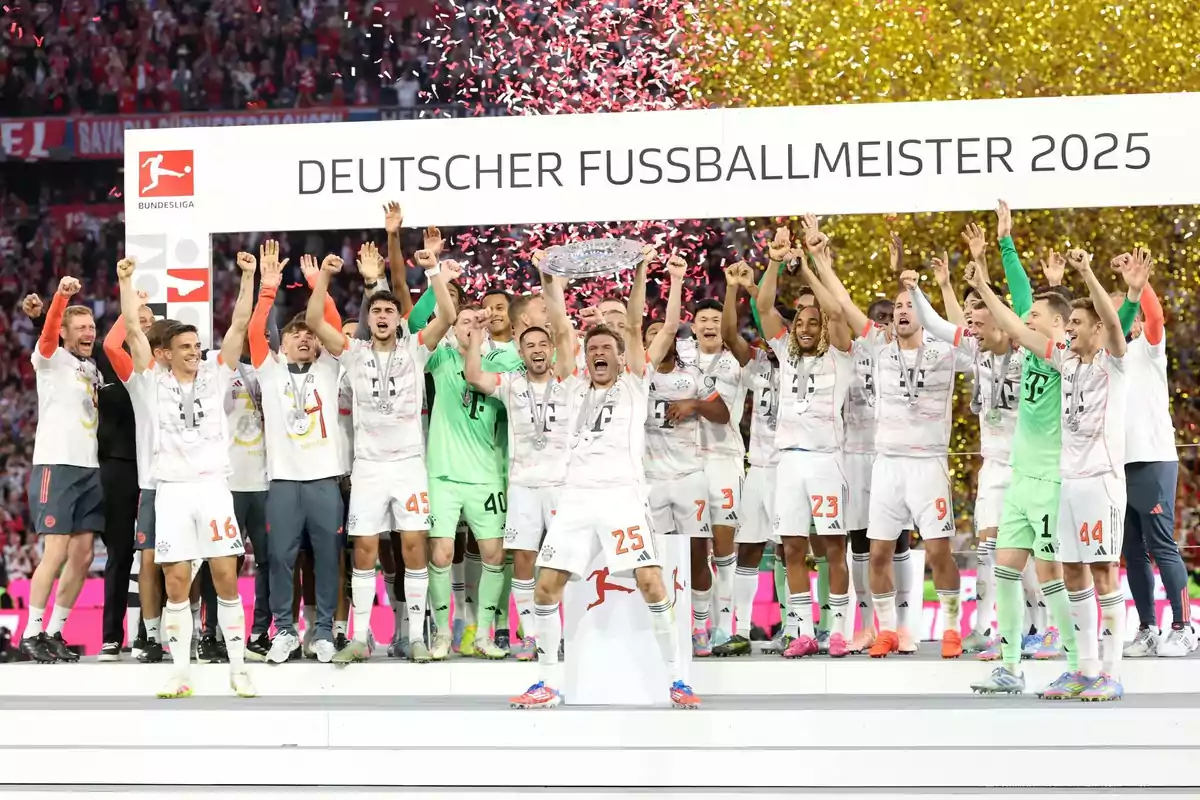 Jugadores de un equipo de fútbol celebran con un trofeo en el podio mientras cae confeti y un letrero al fondo dice Deutscher Fussballmeister 2025 Jugadores de un equipo de fútbol celebran con un trofeo en el podio mientras cae confeti y un letrero al fondo dice Deutscher Fussballmeister 2025