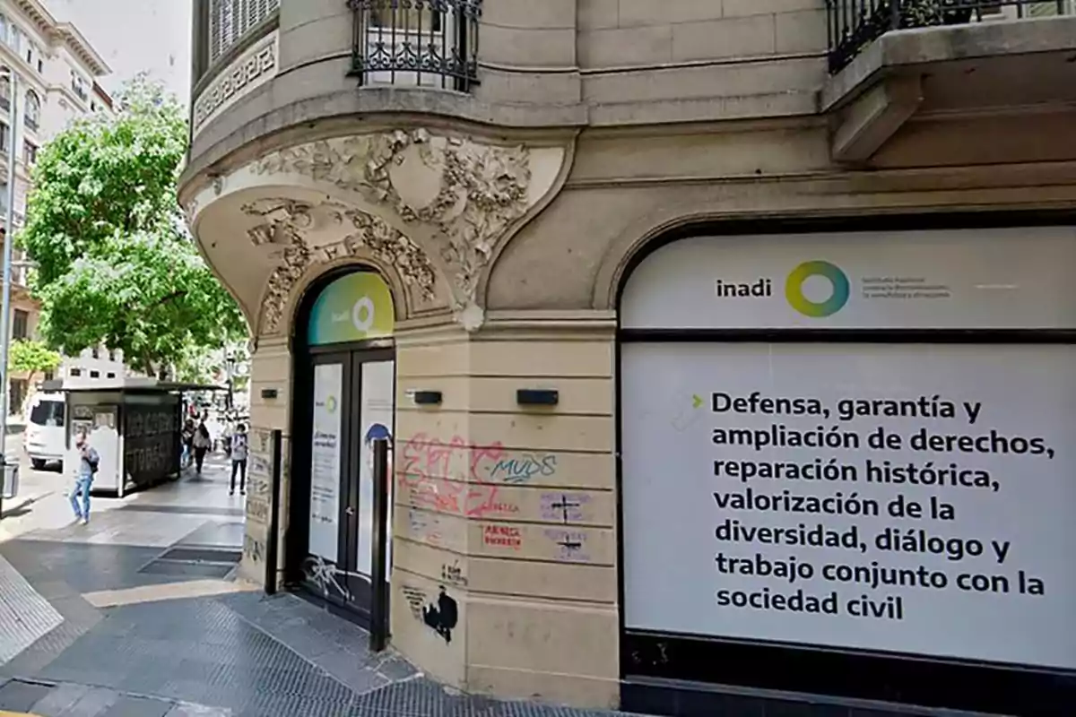 Edificio de esquina con fachada decorada y un cartel del INADI que menciona la defensa y ampliación de derechos, reparación histórica, valorización de la diversidad, diálogo y trabajo conjunto con la sociedad civil. Edificio de esquina con fachada decorada y un cartel del INADI que menciona la defensa y ampliación de derechos, reparación histórica, valorización de la diversidad, diálogo y trabajo conjunto con la sociedad civil.