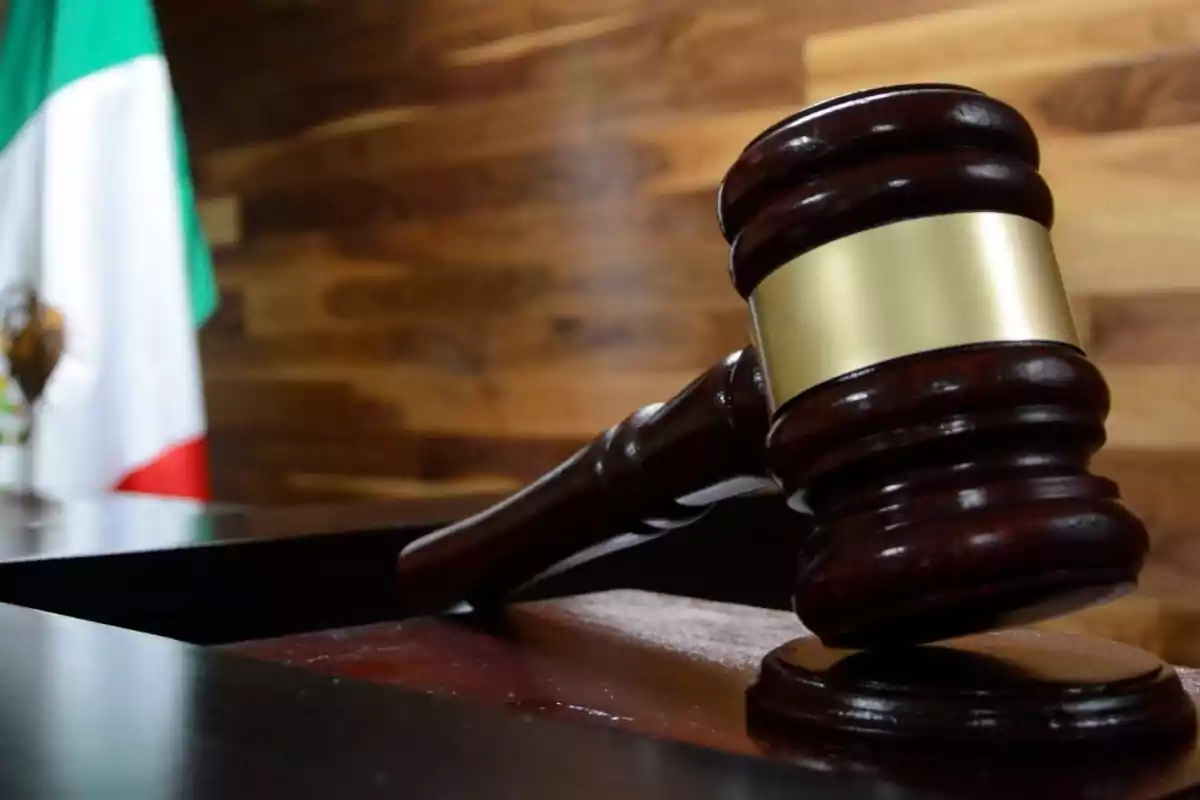 A judge's gavel on a table with a Mexican flag in the background. A judge's gavel on a table with a Mexican flag in the background.