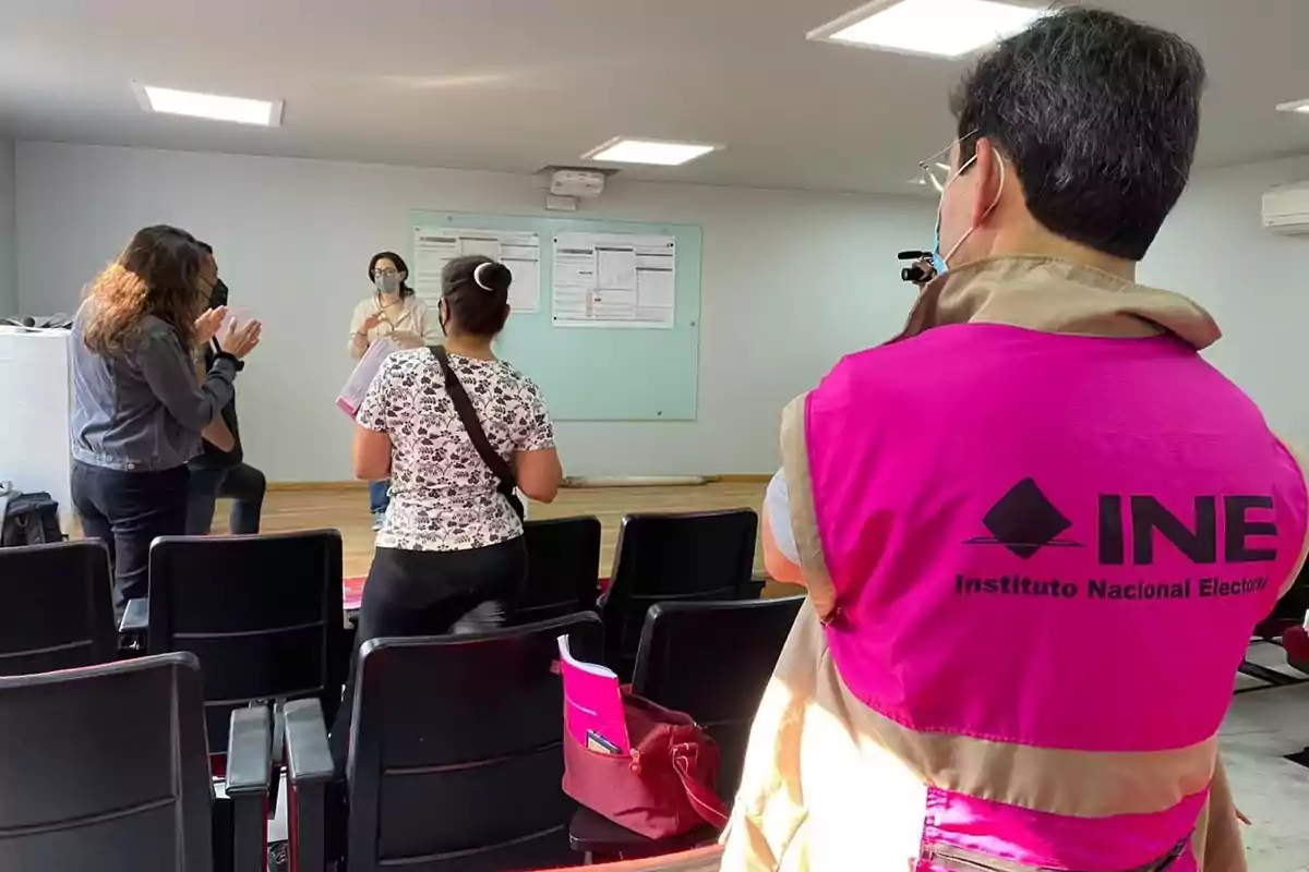 People in a conference room, one of them wearing a vest from the National Electoral Institute. People in a conference room, one of them wearing a vest from the National Electoral Institute.