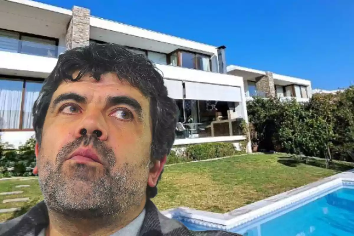 Hombre con barba frente a una casa moderna con jardín y piscina.