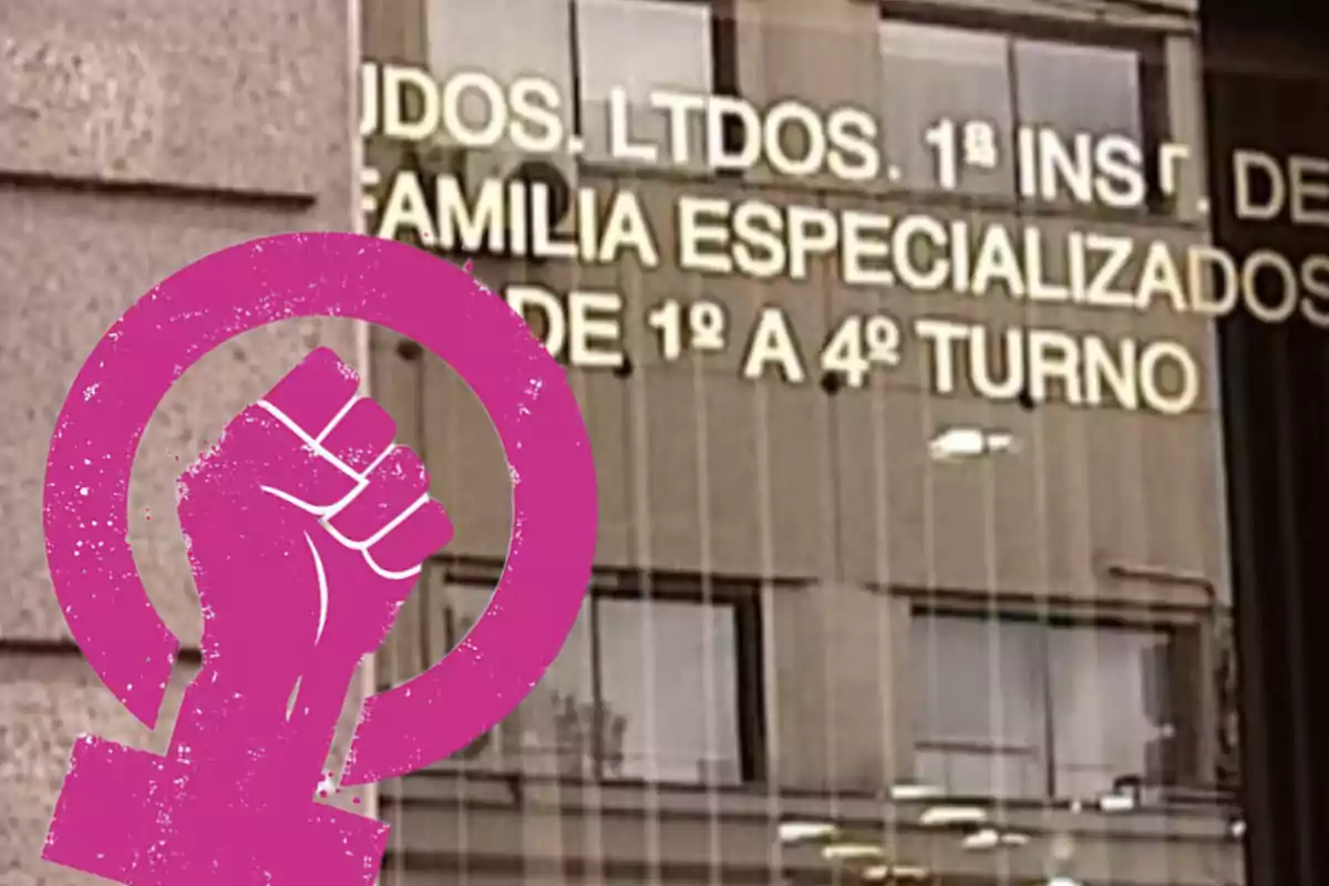 Un edificio con un cartel que tiene texto reflejado en las ventanas y un símbolo feminista rosa en primer plano.