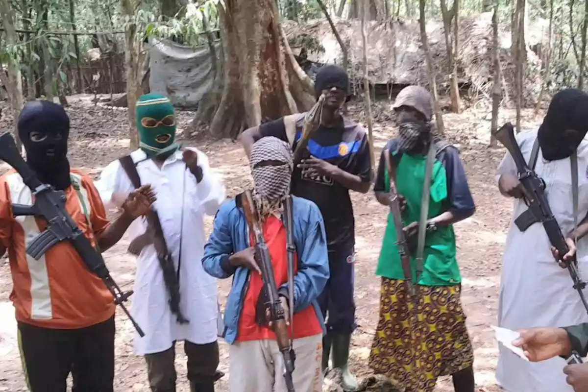 A group of masked people holding weapons in a wooded environment.