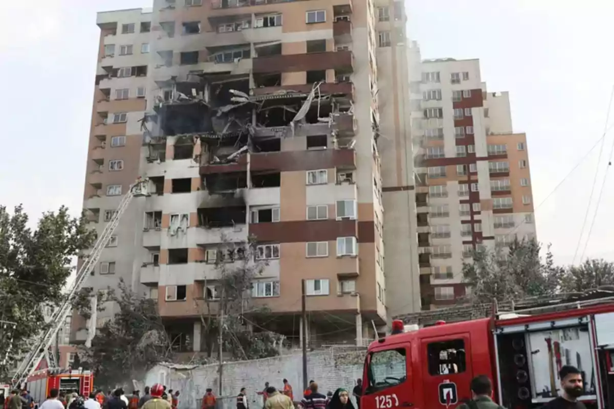 Edificio de apartamentos con graves daños en varios pisos y presencia de bomberos y camiones de emergencia trabajando en el lugar Edificio de apartamentos con graves daños en varios pisos y presencia de bomberos y camiones de emergencia trabajando en el lugar