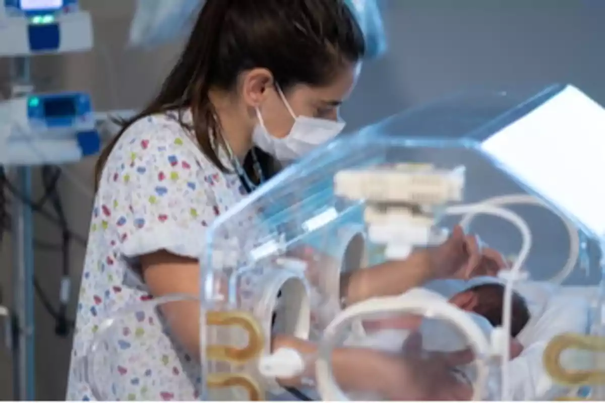 A nurse cares for a baby in an incubator in a hospital setting. A nurse cares for a baby in an incubator in a hospital setting.