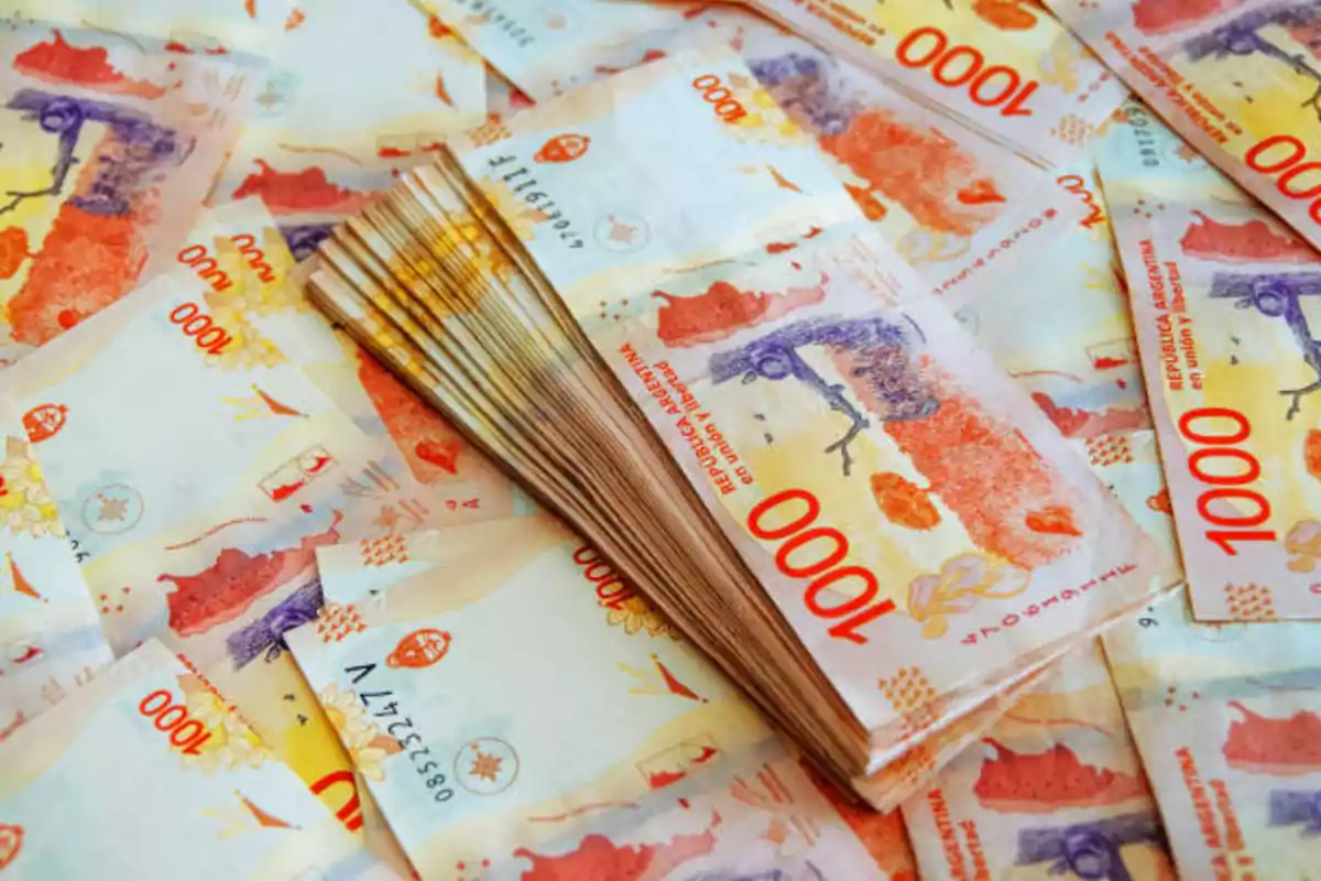 A bunch of one thousand Argentine peso bills stacked and scattered. A bunch of one thousand Argentine peso bills stacked and scattered.