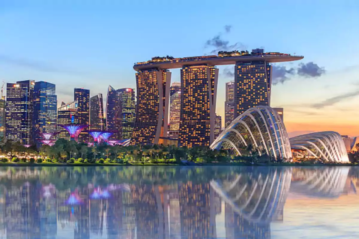 Panoramic view of a modern urban skyline at sunset with illuminated buildings reflecting on the water. Panoramic view of a modern urban skyline at sunset with illuminated buildings reflecting on the water.