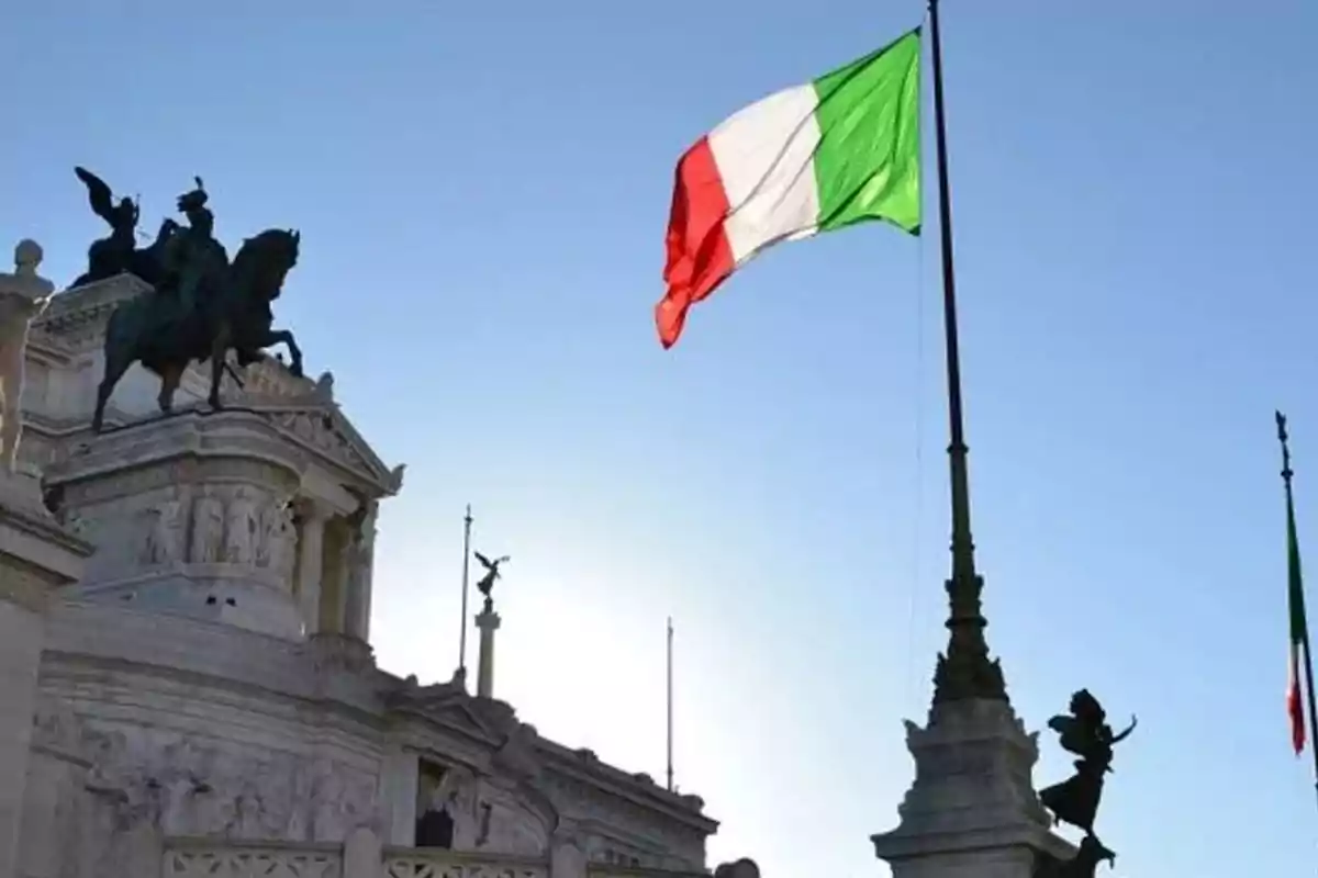 Monument with statues and an Italian flag waving in a clear sky. Monument with statues and an Italian flag waving in a clear sky.
