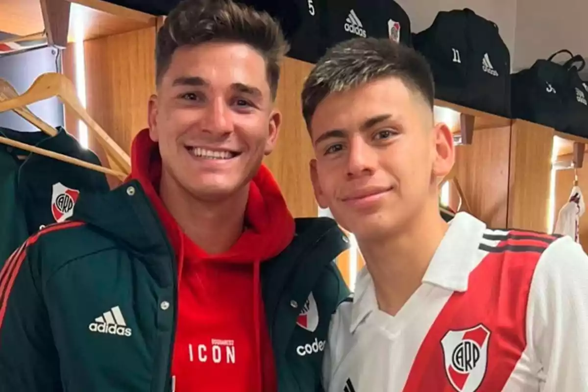 Two people smile in a locker room wearing River Plate soccer team clothing. Two people smile in a locker room wearing River Plate soccer team clothing.