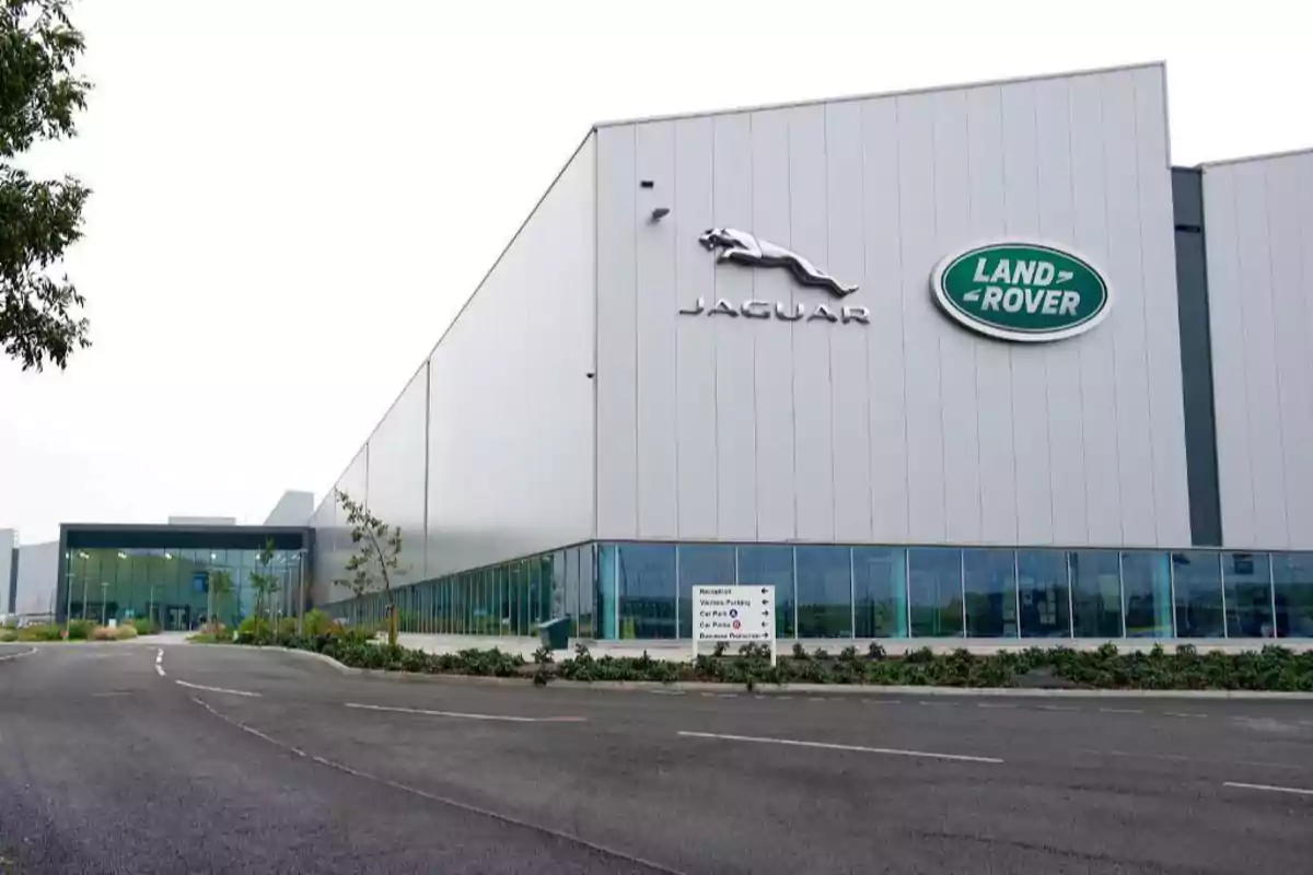 Edificio moderno de Jaguar Land Rover con logotipos en la fachada y un camino de acceso. Edificio moderno de Jaguar Land Rover con logotipos en la fachada y un camino de acceso.