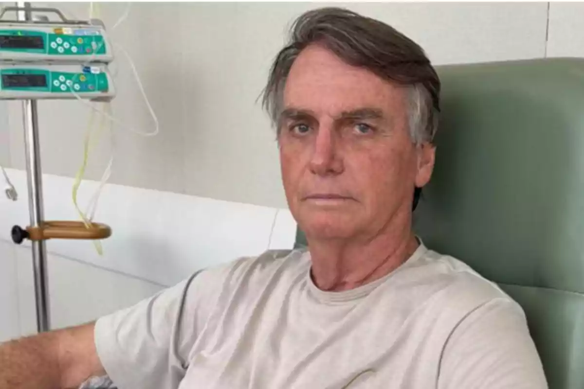 A man sitting in a hospital chair with a serious expression and medical equipment in the background. A man sitting in a hospital chair with a serious expression and medical equipment in the background.