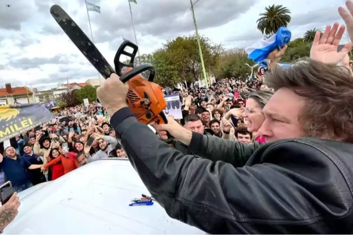 Una persona sostiene una motosierra en un evento al aire libre rodeado de una multitud entusiasta.