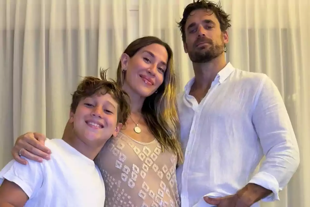 Una familia sonriente posando juntos frente a una cortina blanca.