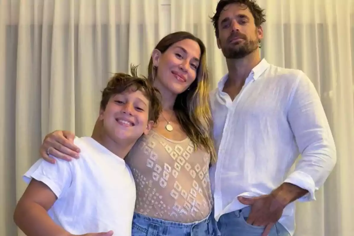 Una familia sonriente posa junta frente a una cortina clara