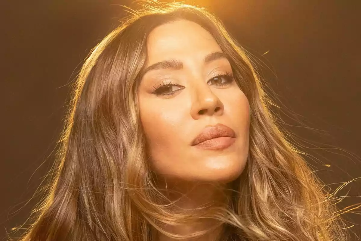 Una persona con cabello largo y suelto iluminada por una luz cálida.
