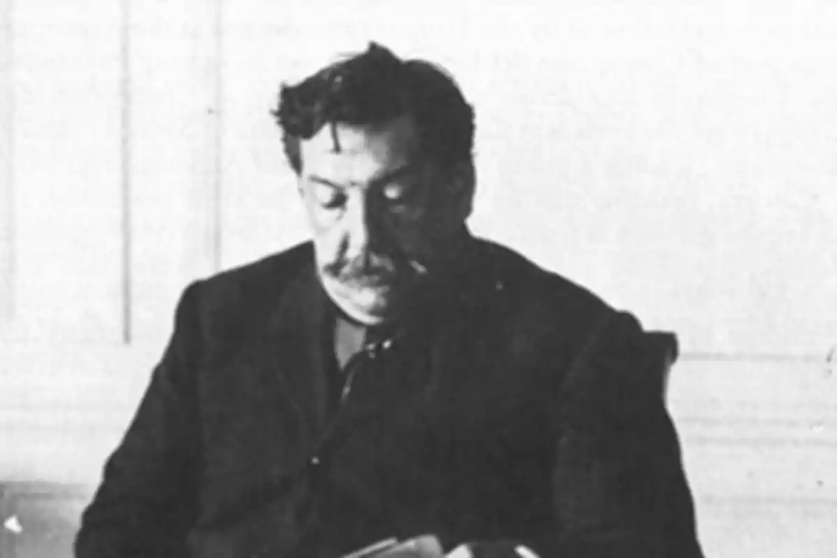 Mustached man sitting and reading a book in a black and white photograph Mustached man sitting and reading a book in a black and white photograph