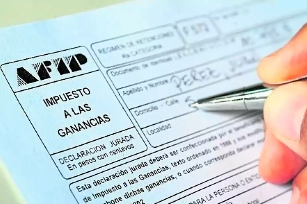 Una persona completando un formulario de declaración jurada de impuestos a las ganancias de la AFIP con un bolígrafo.