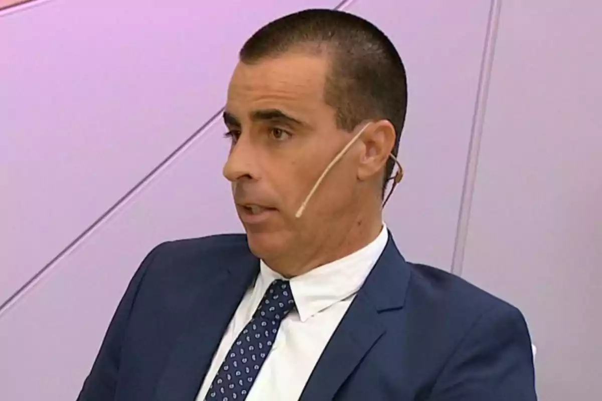 Un hombre con traje y corbata hablando con un micrófono de diadema. Un hombre con traje y corbata hablando con un micrófono de diadema.