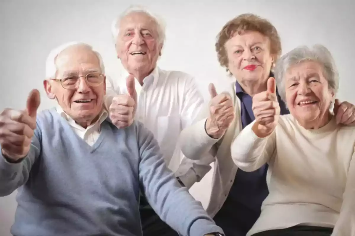 Un grupo de personas mayores sonriendo y levantando el pulgar en señal de aprobación.