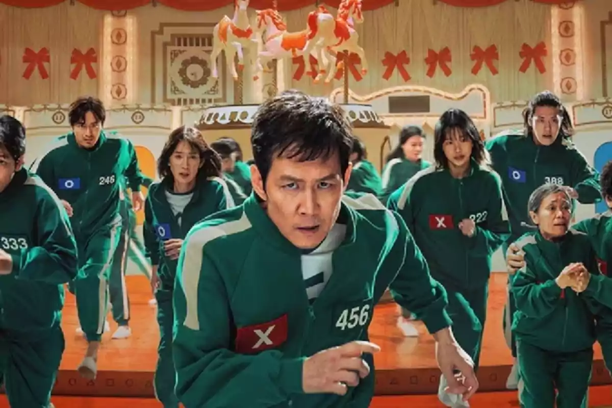 Un grupo de personas con uniformes verdes corren en un entorno que parece un carrusel decorado con caballos y lazos rojos. Un grupo de personas con uniformes verdes corren en un entorno que parece un carrusel decorado con caballos y lazos rojos.