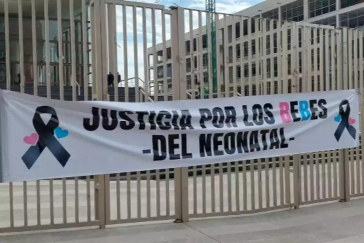 Pancarta blanca colgada en una reja con la frase justicia por los bebes del neonatal acompañada de listones negros y corazones rosas y azules Pancarta blanca colgada en una reja con la frase justicia por los bebes del neonatal acompañada de listones negros y corazones rosas y azules