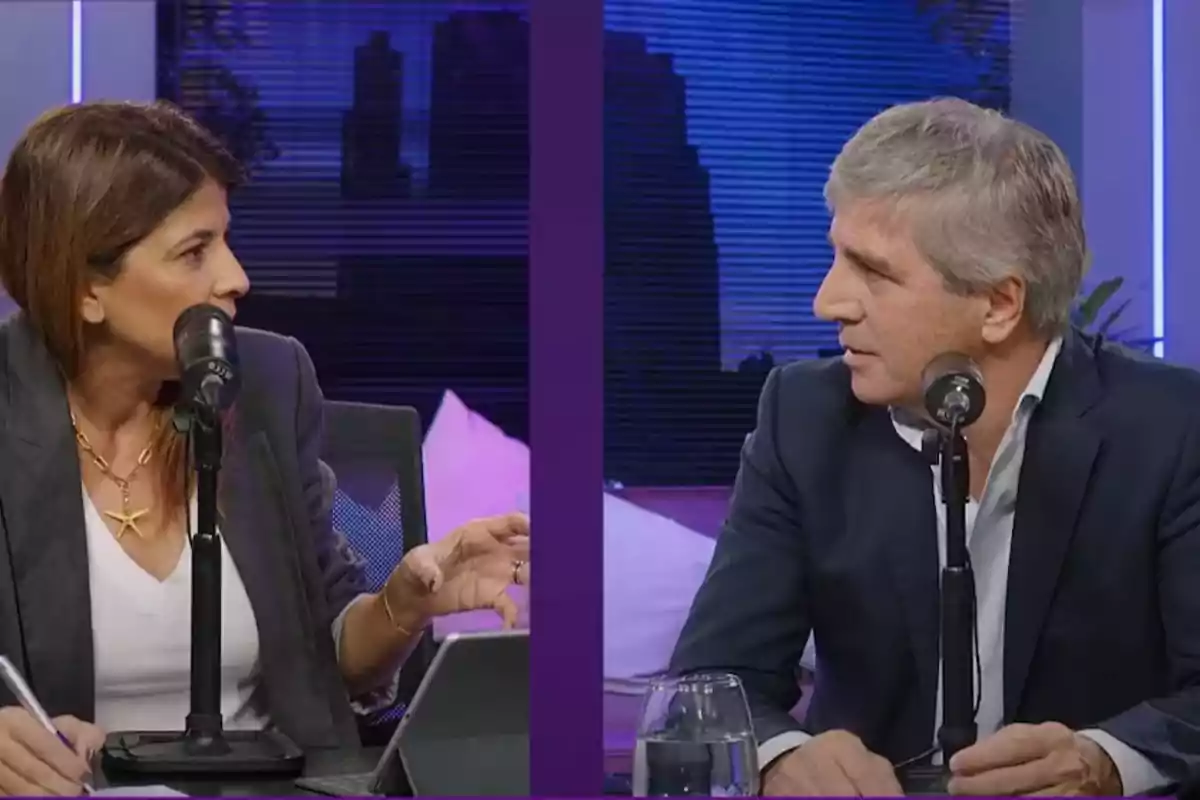 Two people are talking in front of microphones in a recording studio with a lit-up city background. Two people are talking in front of microphones in a recording studio with a lit-up city background.