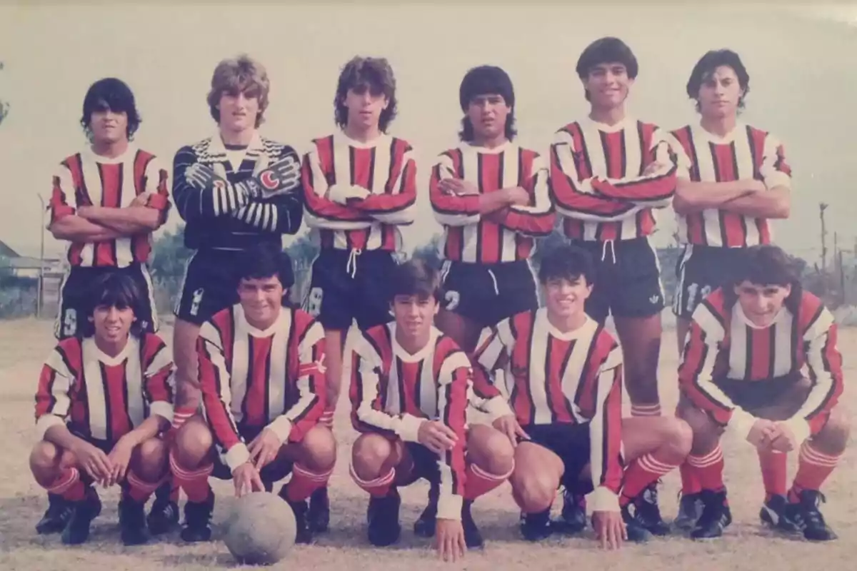 Youth soccer team posing on a dirt field wearing red, white, and black striped jerseys Youth soccer team posing on a dirt field wearing red, white, and black striped jerseys
