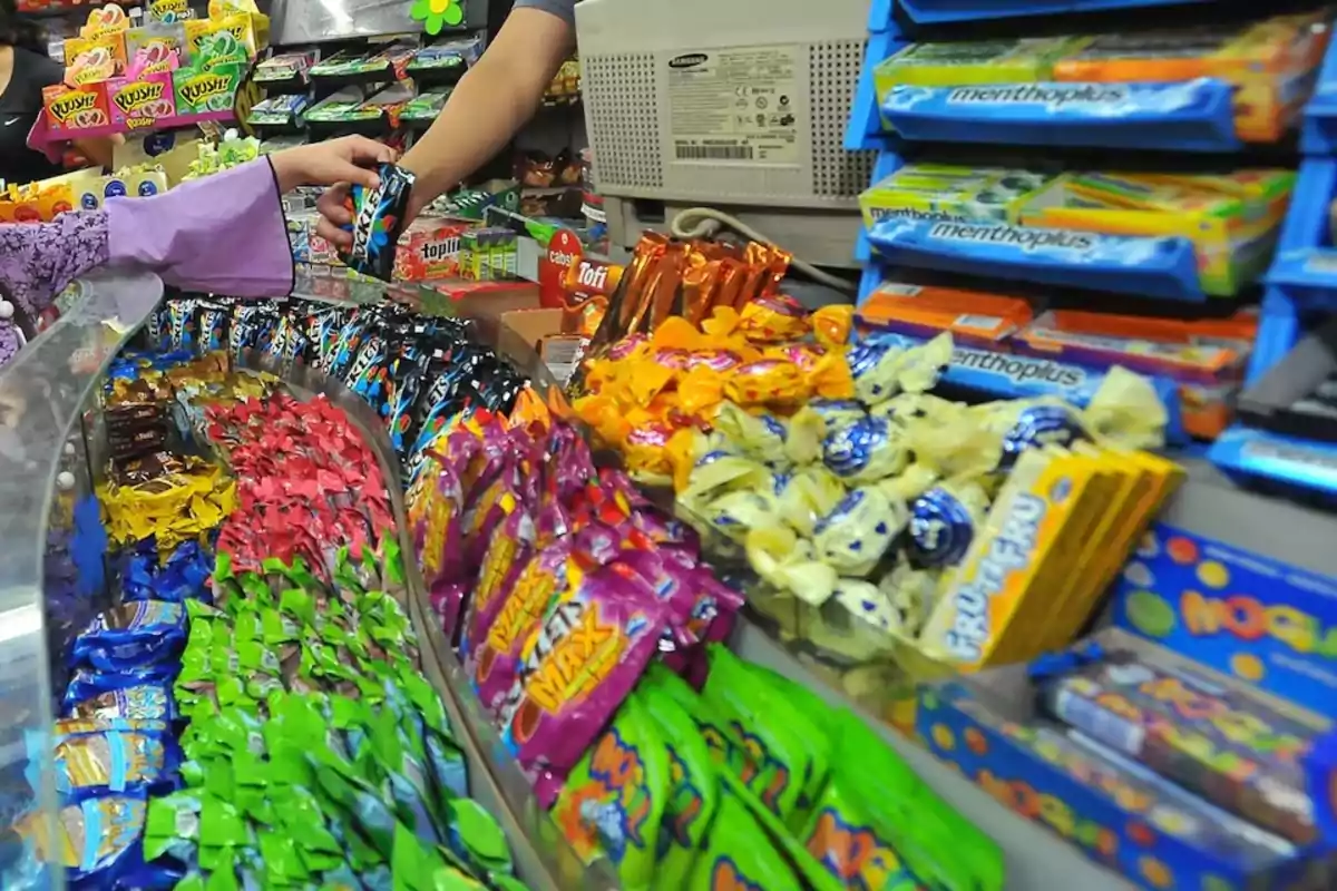 Candy store counter with a wide variety of sweets and two people making a purchase