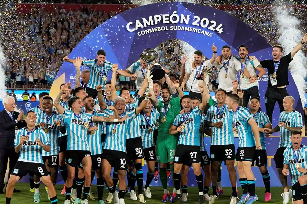 Jugadores de fútbol celebran con el trofeo de la Copa Sudamericana 2024 bajo un arco decorativo, rodeados de confeti y emoción.