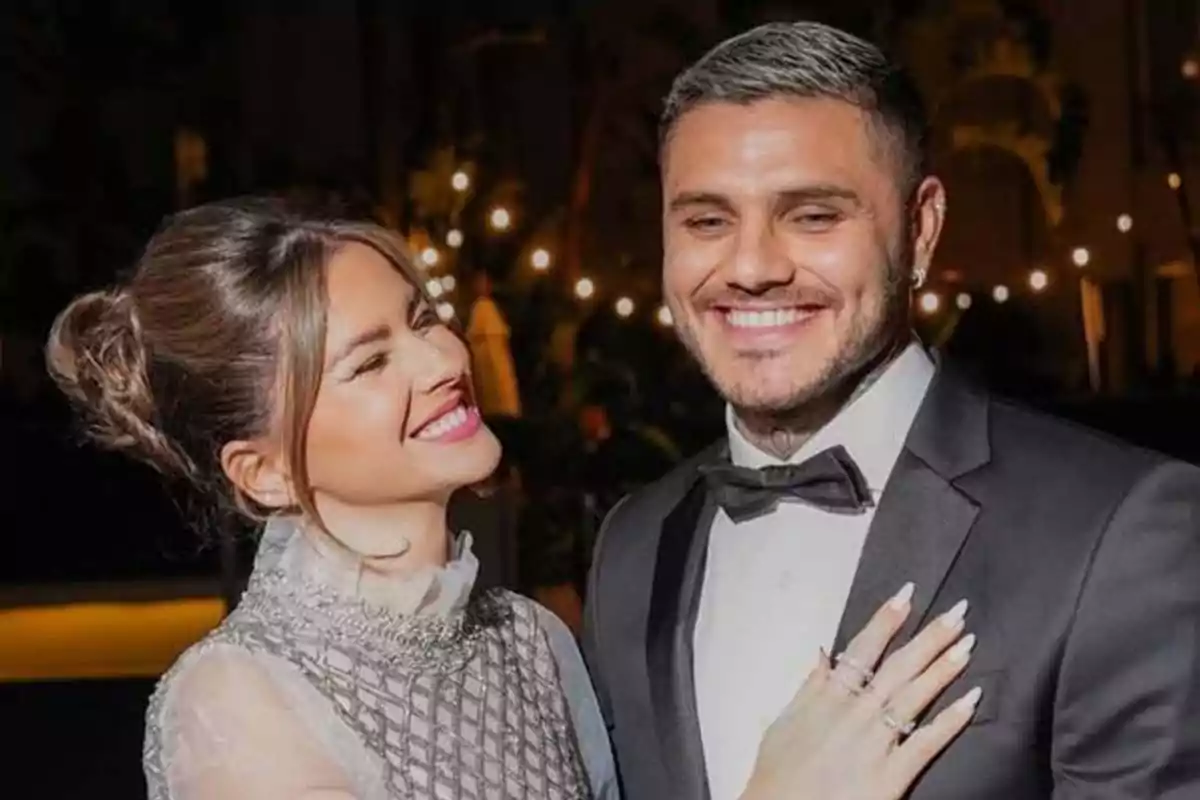 Una pareja sonriente vestida de gala en un evento nocturno con luces de fondo. Una pareja sonriente vestida de gala en un evento nocturno con luces de fondo.