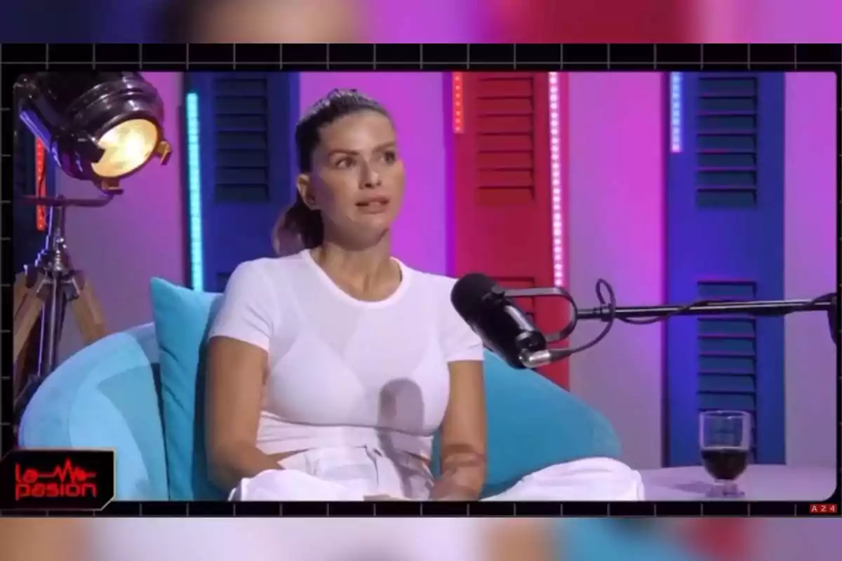 Una persona sentada en un estudio de grabación con micrófono y luces de colores de fondo. Una persona sentada en un estudio de grabación con micrófono y luces de colores de fondo.