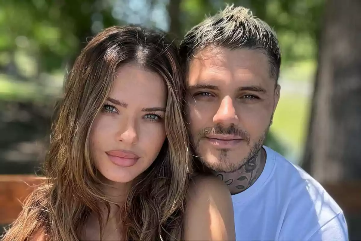 Una pareja posando al aire libre con árboles de fondo.