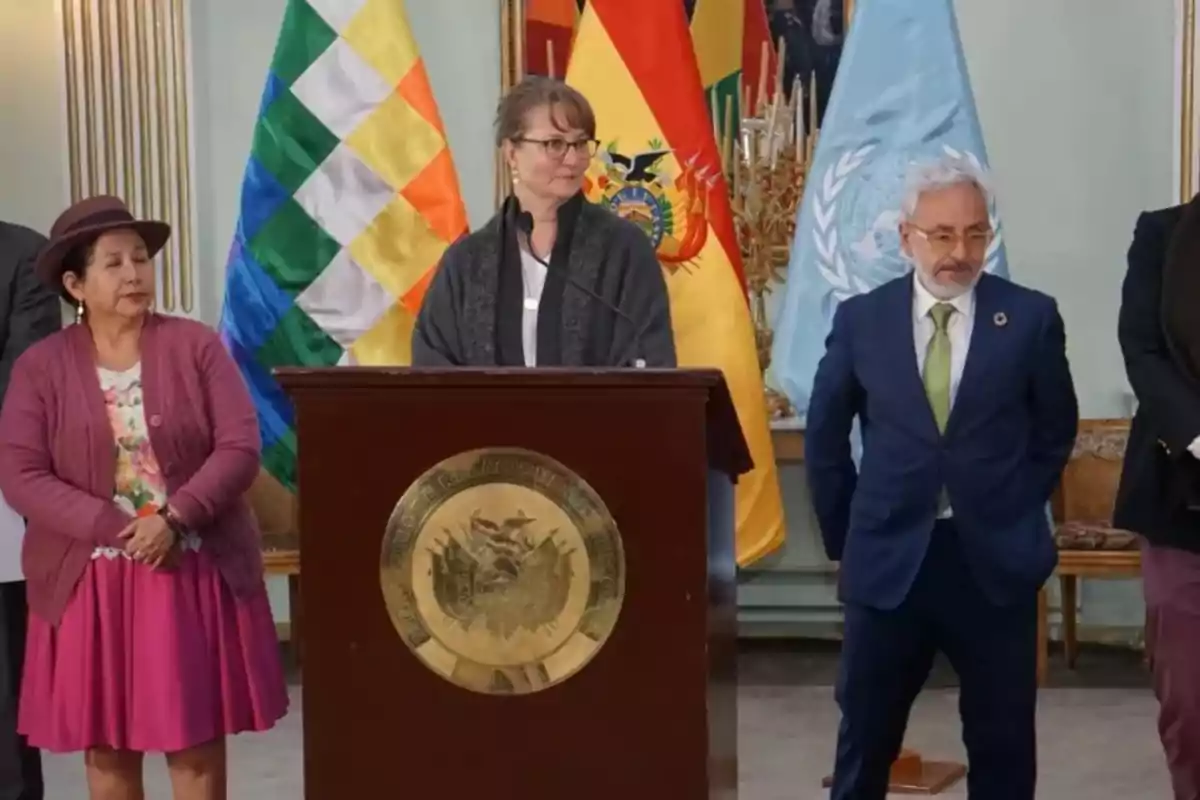 Several people standing next to a podium at an official event with the flags of Bolivia and the UN in the background Several people standing next to a podium at an official event with the flags of Bolivia and the UN in the background