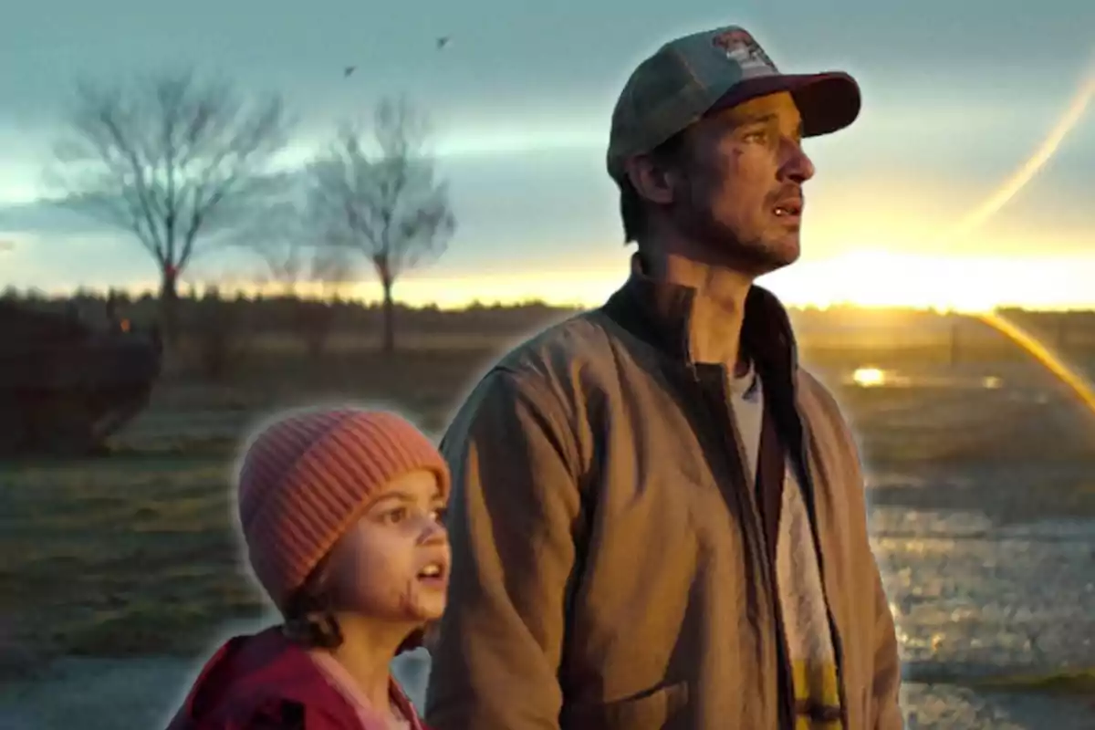 Un hombre y una niña miran hacia el horizonte al atardecer en un paisaje rural.