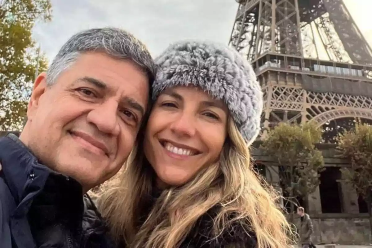 Una pareja sonriente se toma una selfie frente a la Torre Eiffel en París.