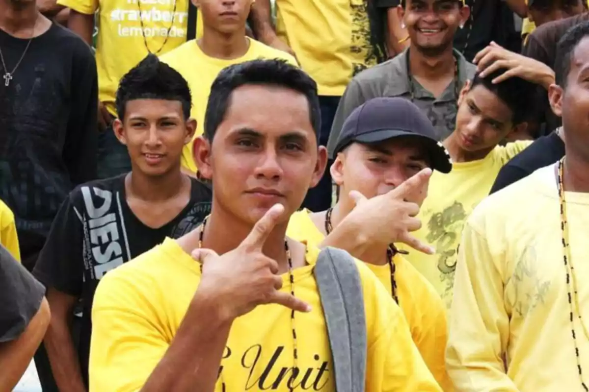 Group of young people posing together wearing yellow t-jerseys and making hand signs