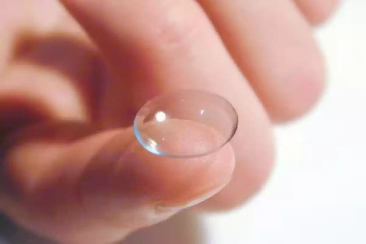 A person is holding a transparent contact lens on the tip of their index finger. A person is holding a transparent contact lens on the tip of their index finger.