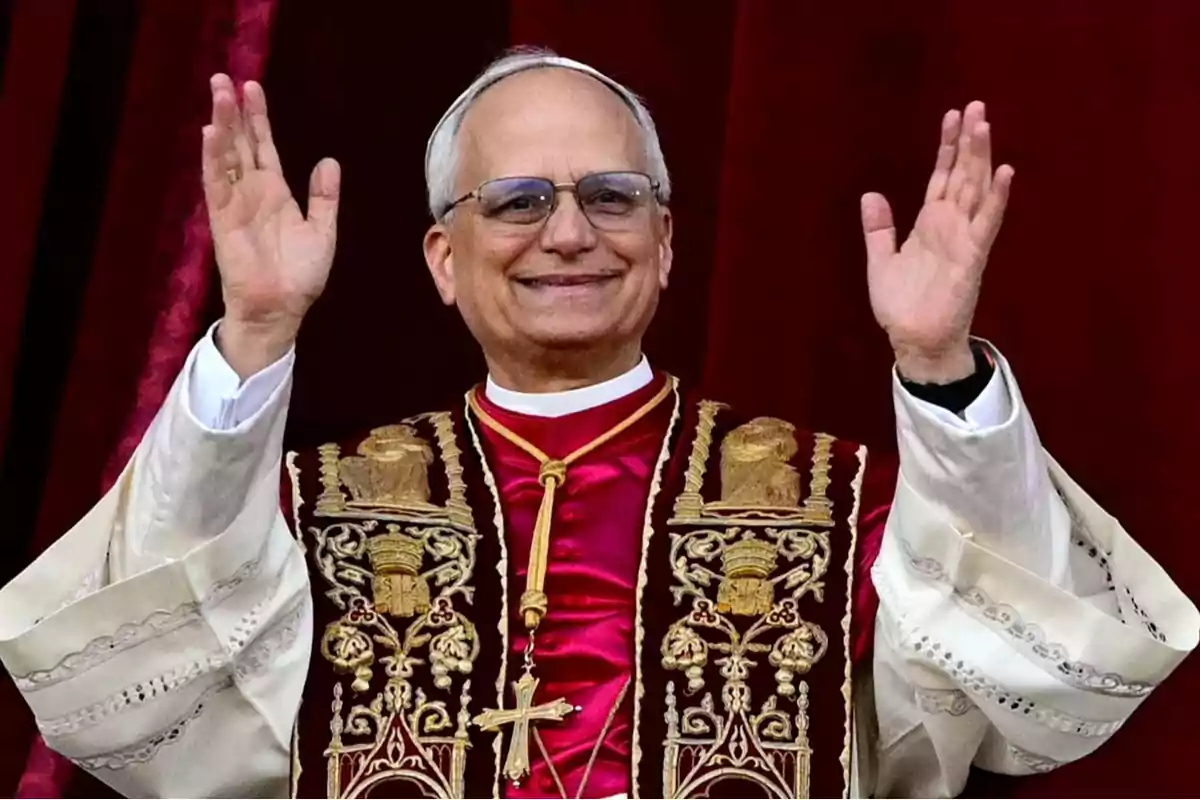 A man in religious attire raising his hands and smiling.
