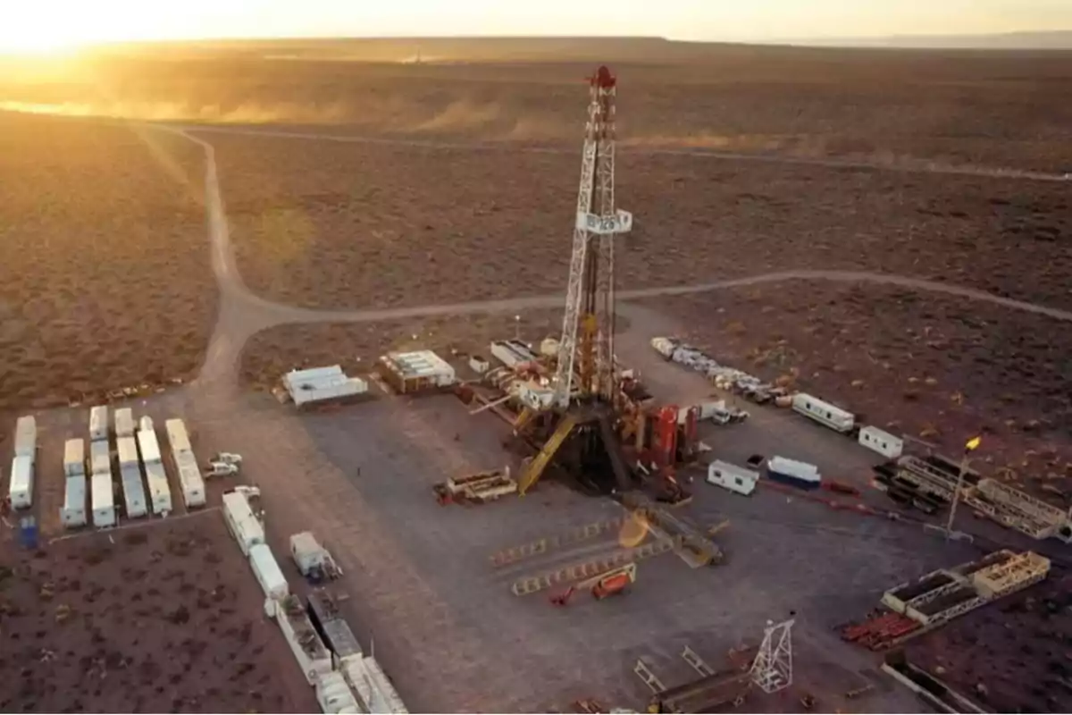 Aerial view of a drilling rig in a desert landscape at sunset.